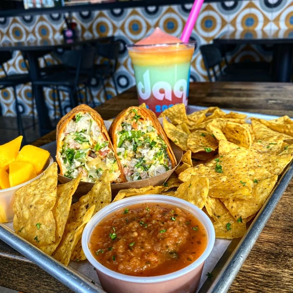 Daiquiri Factory's burritos, tortilla chips, salsa, mango, and a colorful frozen daiquiri on a tray.